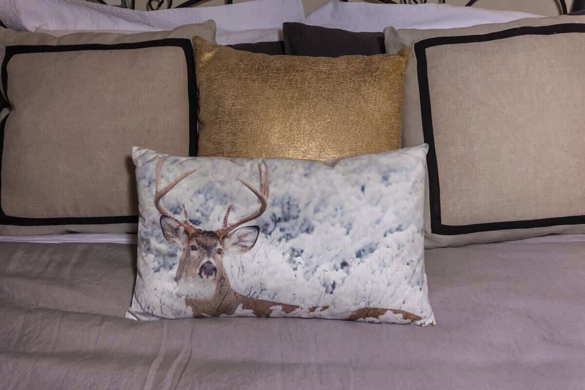 Un lit avec un oreiller à motifs, un oreiller décoratif doré et un oreiller uni.