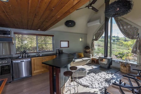 A modern kitchen with a large island, stainless steel appliances, and a view of greenery outside.. Glasshouse | near snowfields &views | spa &logfire