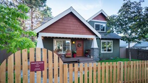 A house with a wooden fence, a front porch, and a sign indicating the name and contact information. - ~LARGE WESTSIDE HOME~ Walk to everything! Welcome to KINGSTON HOUSE (Bend)