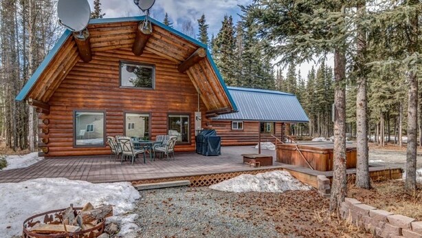 A log cabin with a deck, outdoor seating, and a fire pit. - Sashas Place Kenai River Alaskan Log Cabin with HOT TUB - Maintained Daily (Soldotna)