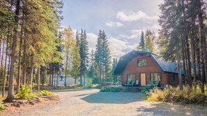 A rustic cabin with a gravel driveway, surrounded by tall trees and a clear sky. - Sashas Place Kenai River Alaskan Log Cabin with HOT TUB - Maintained Daily (Soldotna)