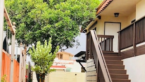 Un barrio residencial con una escalera que lleva a una casa, rodeado de vegetación y un cielo despejado.