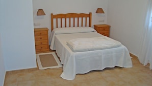 A small, neatly made bed with a wooden headboard in a room with white walls and a tiled floor. - APARTMENT IN RURAL HOUSE OF SANXENXO, AREA NEAR THE SEA WITH WIFI and FREE PARKING (Sanxenxo)