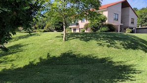 A well-maintained lawn with a single tree and a two-story building with balconies. - APARTMENT IN RURAL HOUSE OF SANXENXO, AREA NEAR THE SEA WITH WIFI and FREE PARKING (Sanxenxo)