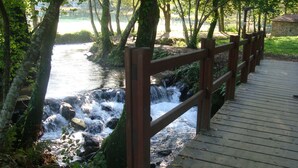 A wooden boardwalk with a wooden railing, leading to a rocky stream surrounded by trees. - APARTMENT IN RURAL HOUSE OF SANXENXO, AREA NEAR THE SEA WITH WIFI and FREE PARKING (Sanxenxo)