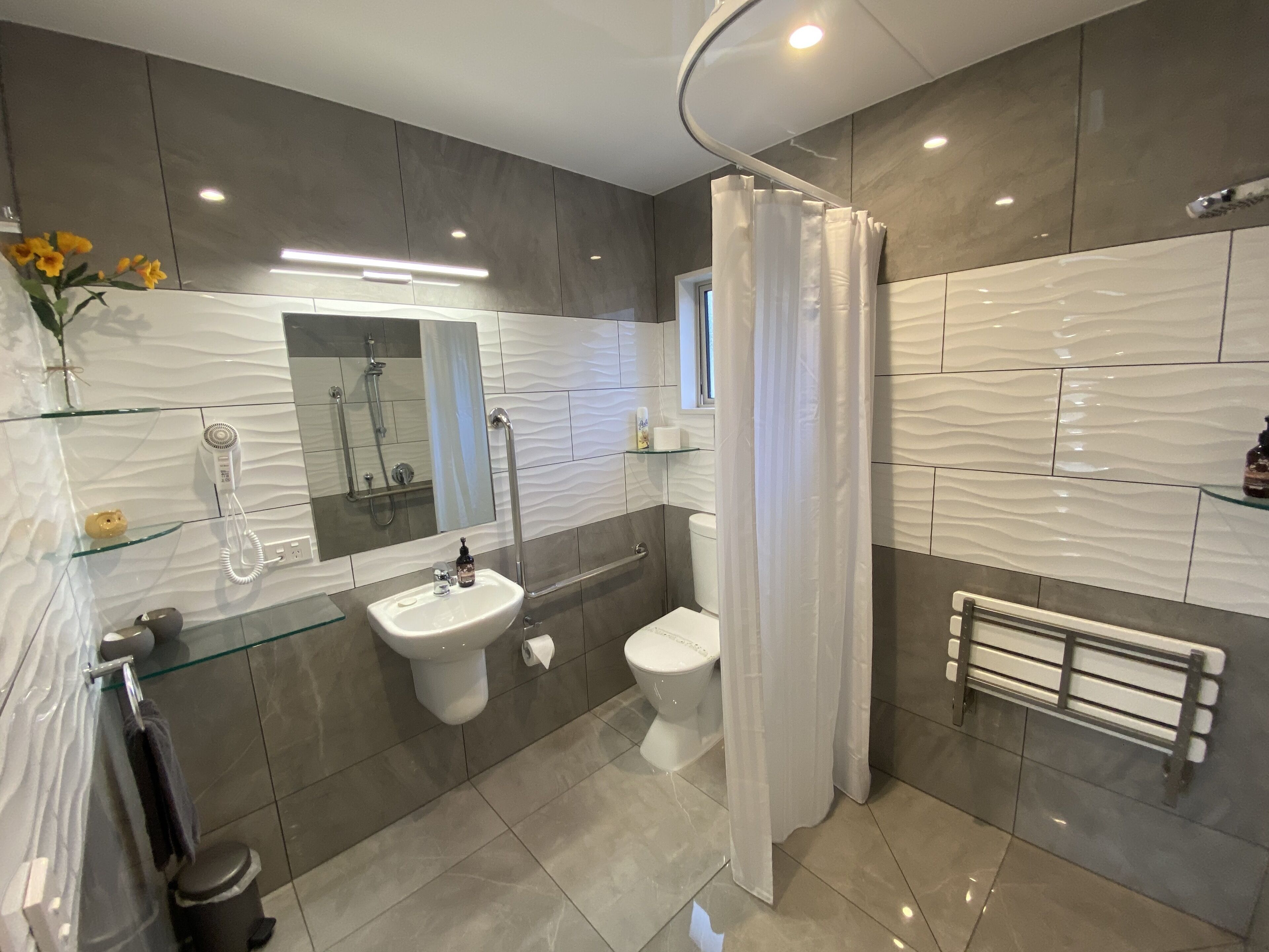 Un baño moderno con cabina de ducha de vidrio, un lavamanos blanco y un inodoro.