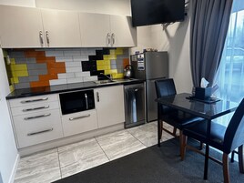Una cocina moderna con armarios blancos, encimera negra y salpicadero colorido.