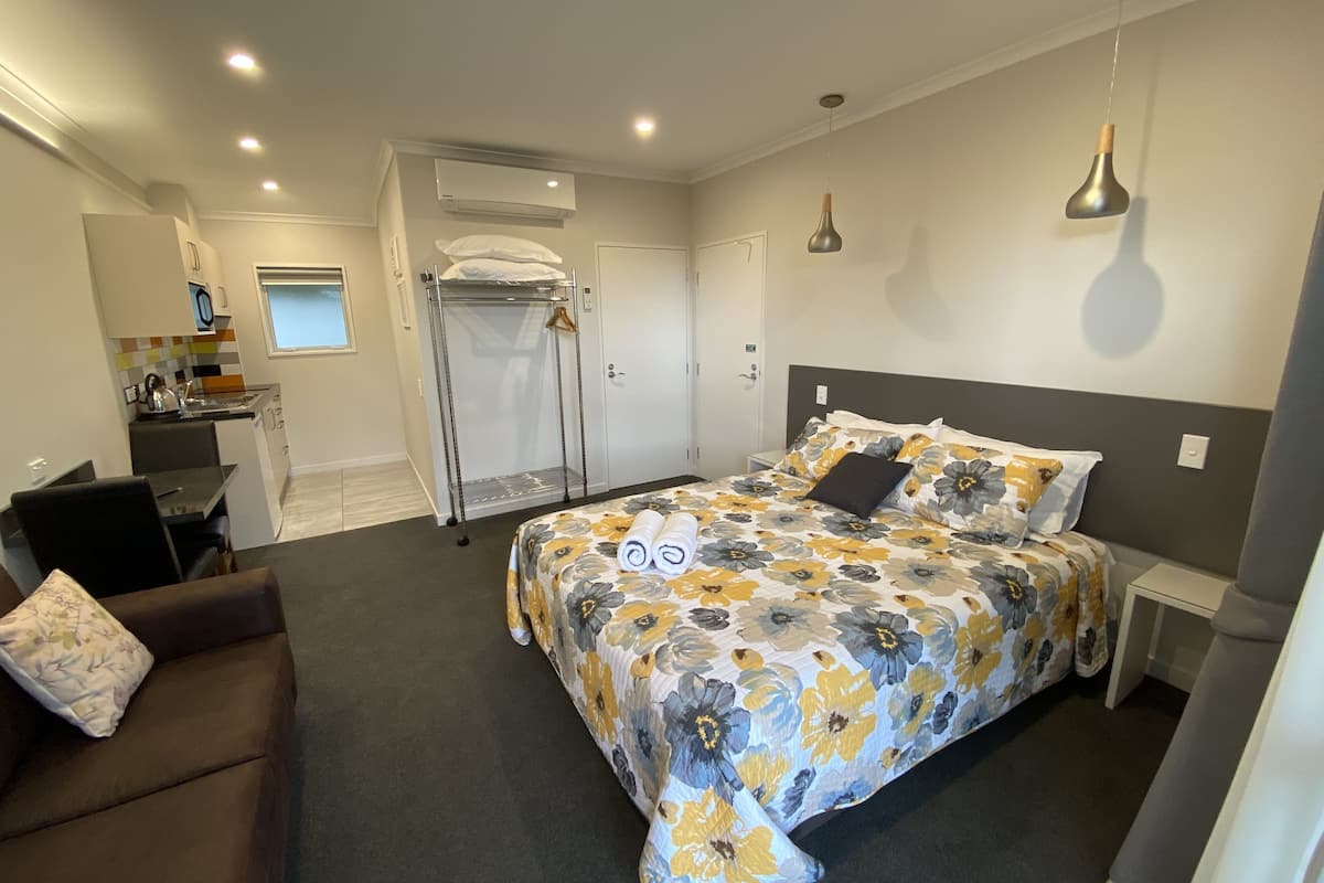 A bedroom with a bed, a desk, a chair, a wardrobe, and an air conditioning unit.