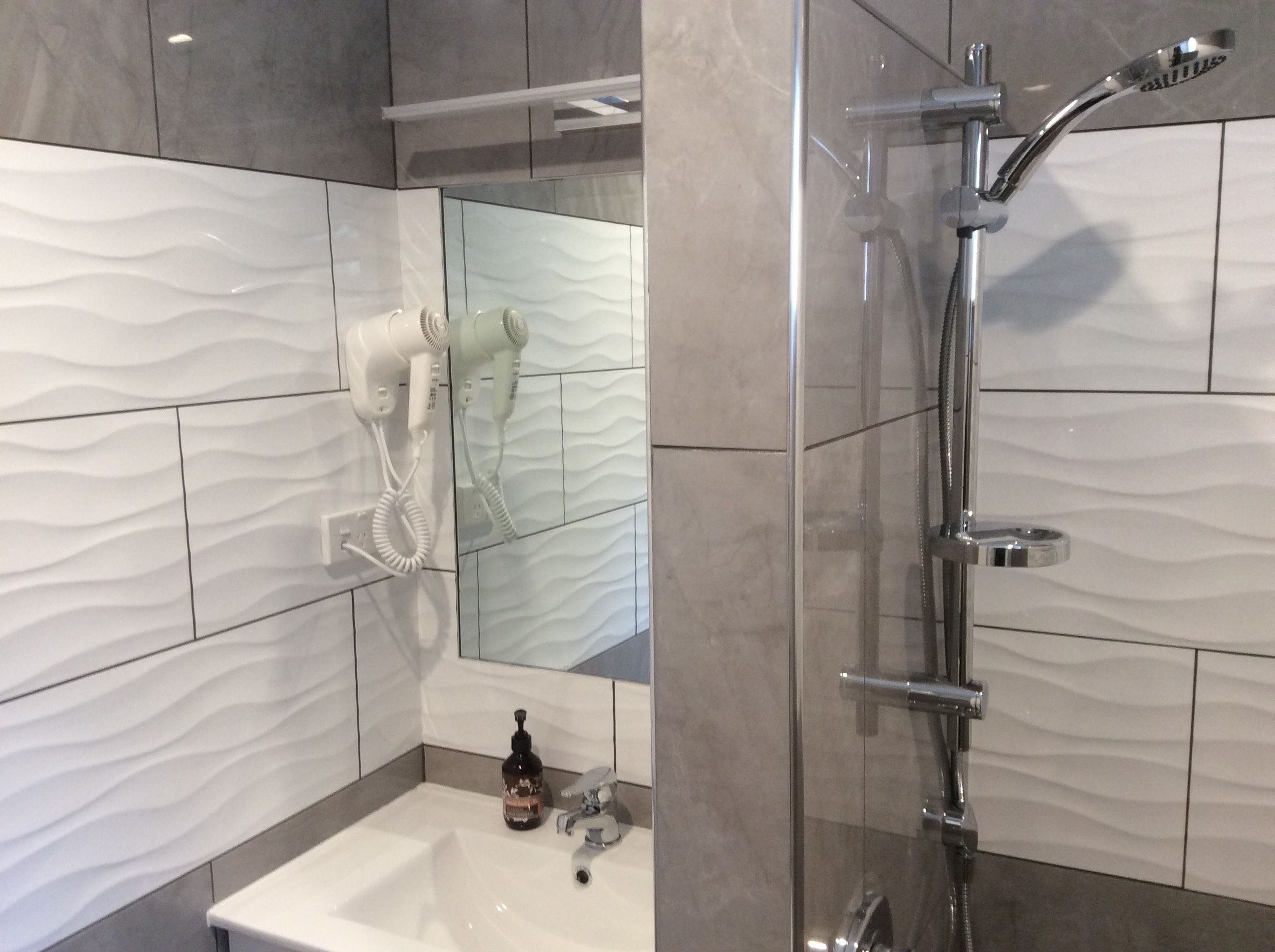 A bathroom with a shower, a sink, and a mirror.