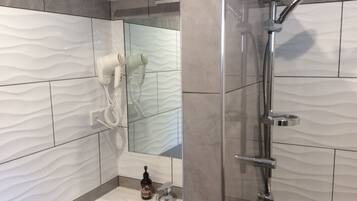 A bathroom with a shower, a sink, and a mirror.
