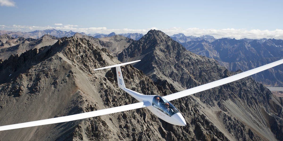 A small aircraft flying over a mountainous landscape.
