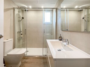 Une salle de bain moderne avec une douche à parois de verre, un lavabo blanc et des toilettes.