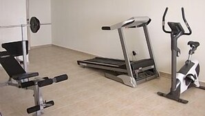 Ein Fitnessstudio mit Laufband, Crosstrainer und Gewichtbank.