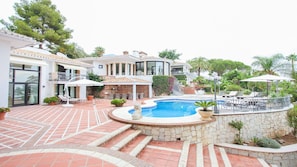 A residential property with a swimming pool, outdoor seating, and a stone wall.