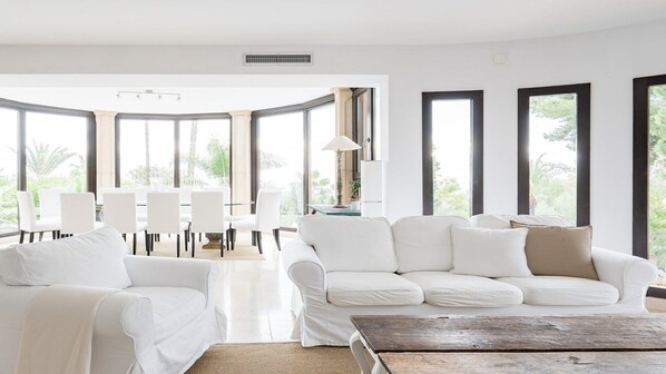 Een moderne woonkamer met een witte bank, een salontafel en een eethoek met witte stoelen en een tafel.