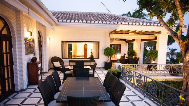 Un patio con suelo de baldosas, una mesa de comedor con sillas y una pérgola.