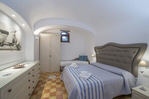 Un dormitorio con cama, cómoda, armario, ventana y lámpara fijada a la pared.