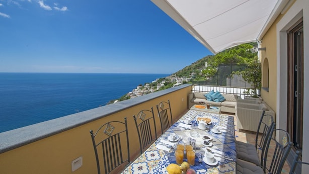 A balcony with a table set for dining, overlooking a coastal view. - Golden Vaults, at few stairs from the road. It is easy to park in the area (Praiano)