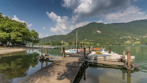 A wooden dock extending into calm water with boats docked at the end. - Holiday House - "RESIDENCE LAGO DI ENDINE" (Monasterolo del Castello)