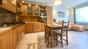 A modern kitchen with wooden cabinets, a dining table with chairs, and a pendant light. - Holiday House - "RESIDENCE LAGO DI ENDINE" (Monasterolo del Castello)