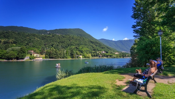 A lakeside view with a grassy area, a bench, and a person with a dog. - Holiday House - "RESIDENCE LAGO DI ENDINE" (Monasterolo del Castello)