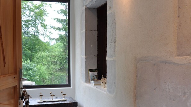 A modern bathroom with a large window, a wooden cabinet, and a stone wall. - CHALET LARGE COMFORT (Le Bouchet-Mont-Charvin)