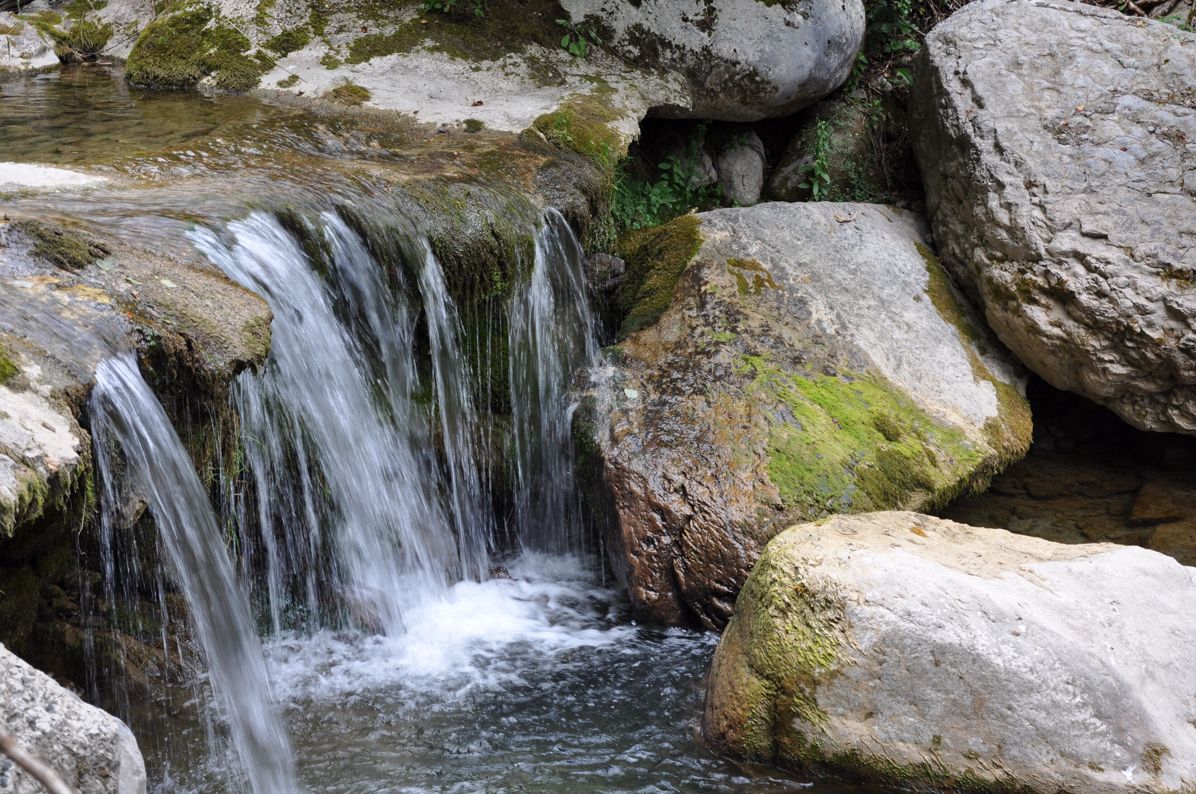 A natural waterfall surrounded by large rocks and moss.