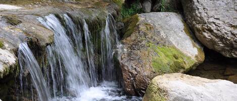 A natural waterfall surrounded by large rocks and moss.