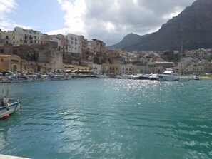 A coastal town with buildings along the waterfront, boats docked, and a mountain in the background.