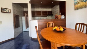 A dining area with a wooden table, chairs, and a fruit bowl.