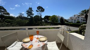 A balcony with a table set for two, a chair, and a railing.
