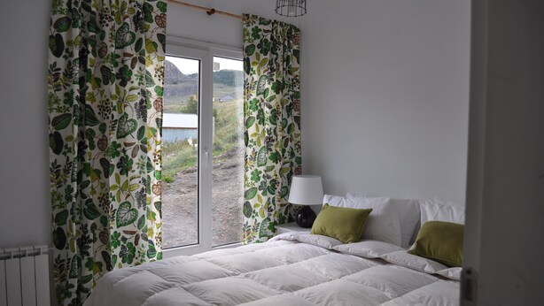 Un dormitorio con cama, mesita de noche y vistas a una masa de agua a través de una ventana.