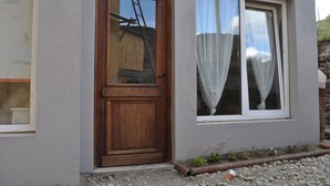 Un edificio con puerta de madera y ventana con cortinas.