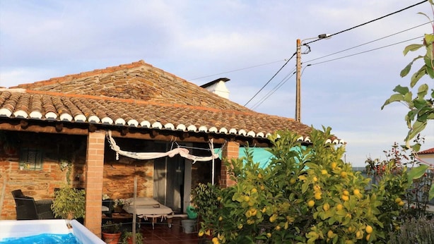 Una casa con tetto in tegole, piscina e un giardino con alberi di limoni.