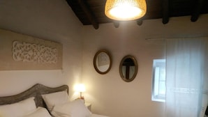 Una camera da letto con un letto, due specchi a parete, un elemento decorativo e una finestra con tende.