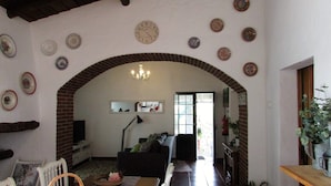 Un soggiorno con un arco in mattoni, una televisione, un divano e diverse piastre decorative appese al muro.