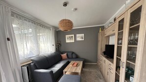 A modern living room with a sectional sofa, a wooden coffee table, a television, and a cabinet with glass doors.