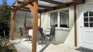 A covered patio with wooden beams, two chairs, and a table.