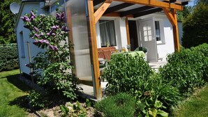 A small, white house with a wooden pergola over a porch.
