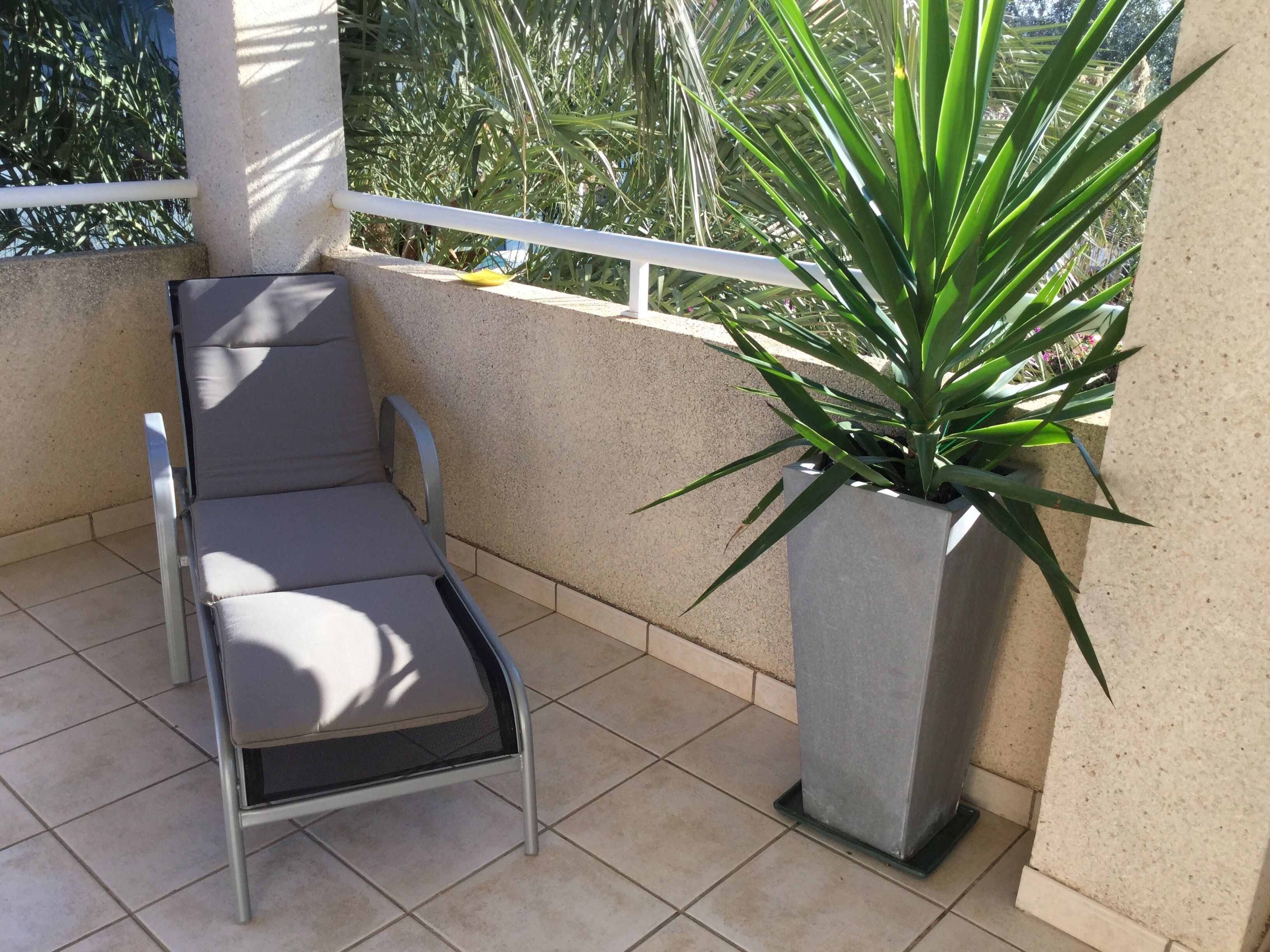 Een balkon met een metalen stoel en een bloempot.