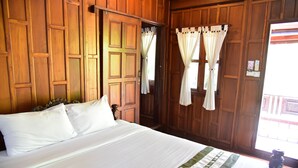 Ein Zimmer mit Holzwänden, einem Bett, Vorhängen und einem Fenster.