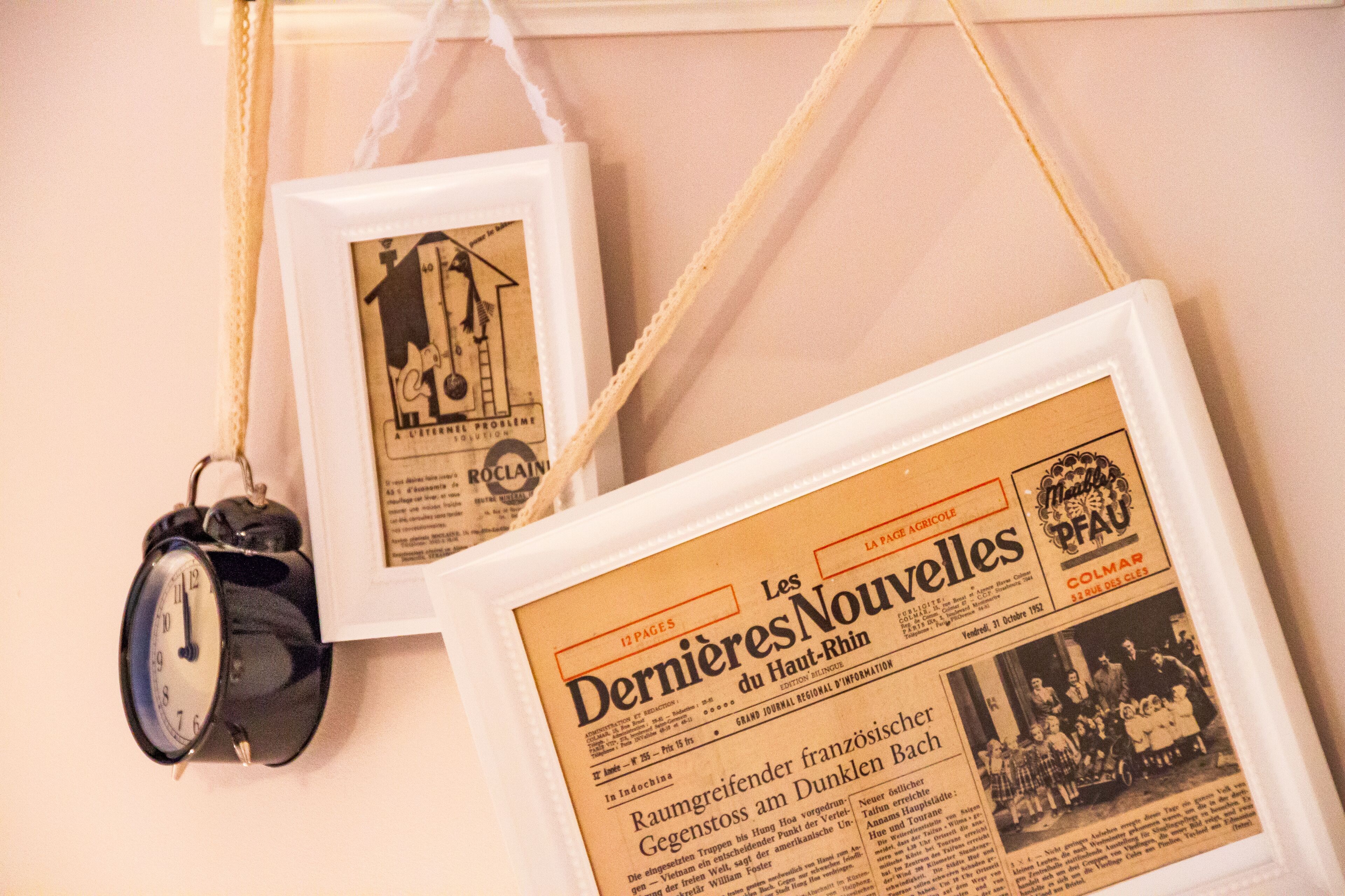 Zwei gerahmte Zeitungsartikel und ein alter Wecker hängen an einer Wand.