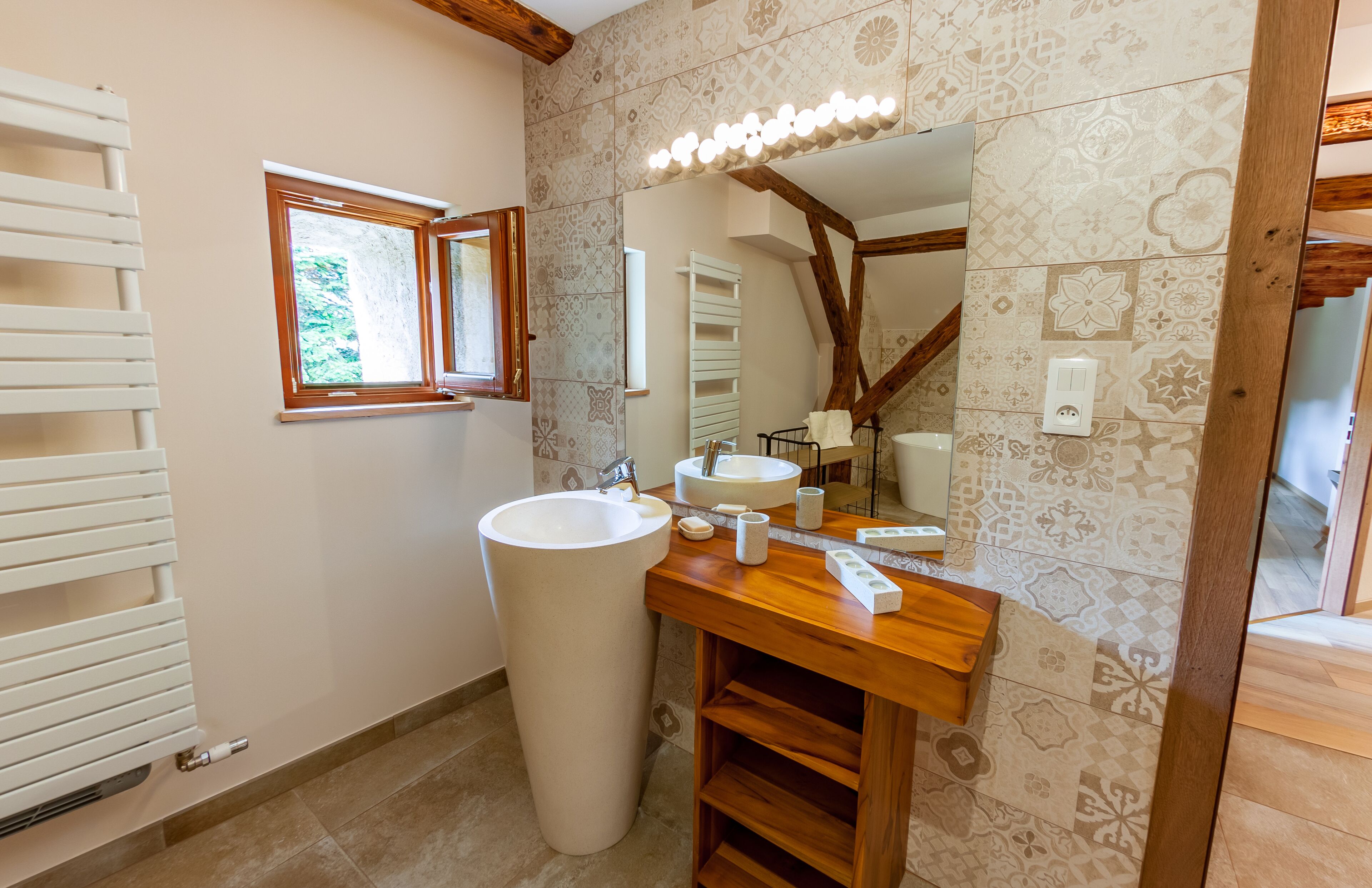 Un bagno con un lavandino grande bianco, un mobile bagno in legno e uno specchio con luci.