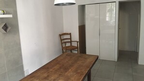 Una habitación con una mesa de madera, una silla, una lámpara colgante blanca y una puerta corrediza.