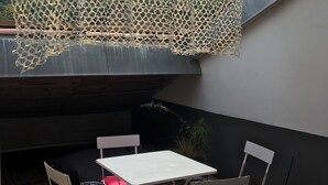 Un espacio al aire libre cubierto con mesas y sillas, una red decorativa y una pared de madera.