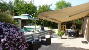 A poolside area with lounge chairs, a covered patio, and a barbecue grill.