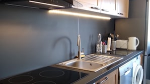 Een moderne keuken met een zwart aanrecht, roestvrijstalen apparatuur, houten kastjes en een ingebouwde oven.