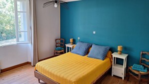 Une chambre à coucher avec un lit en bois, un mur bleu et une fenêtre avec des rideaux.