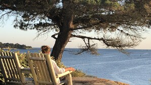 Un banc en bois sur lequel est assis une personne, donnant sur une étendue d’eau.