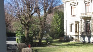 A building with classical architecture, a well-maintained lawn, and a bench.